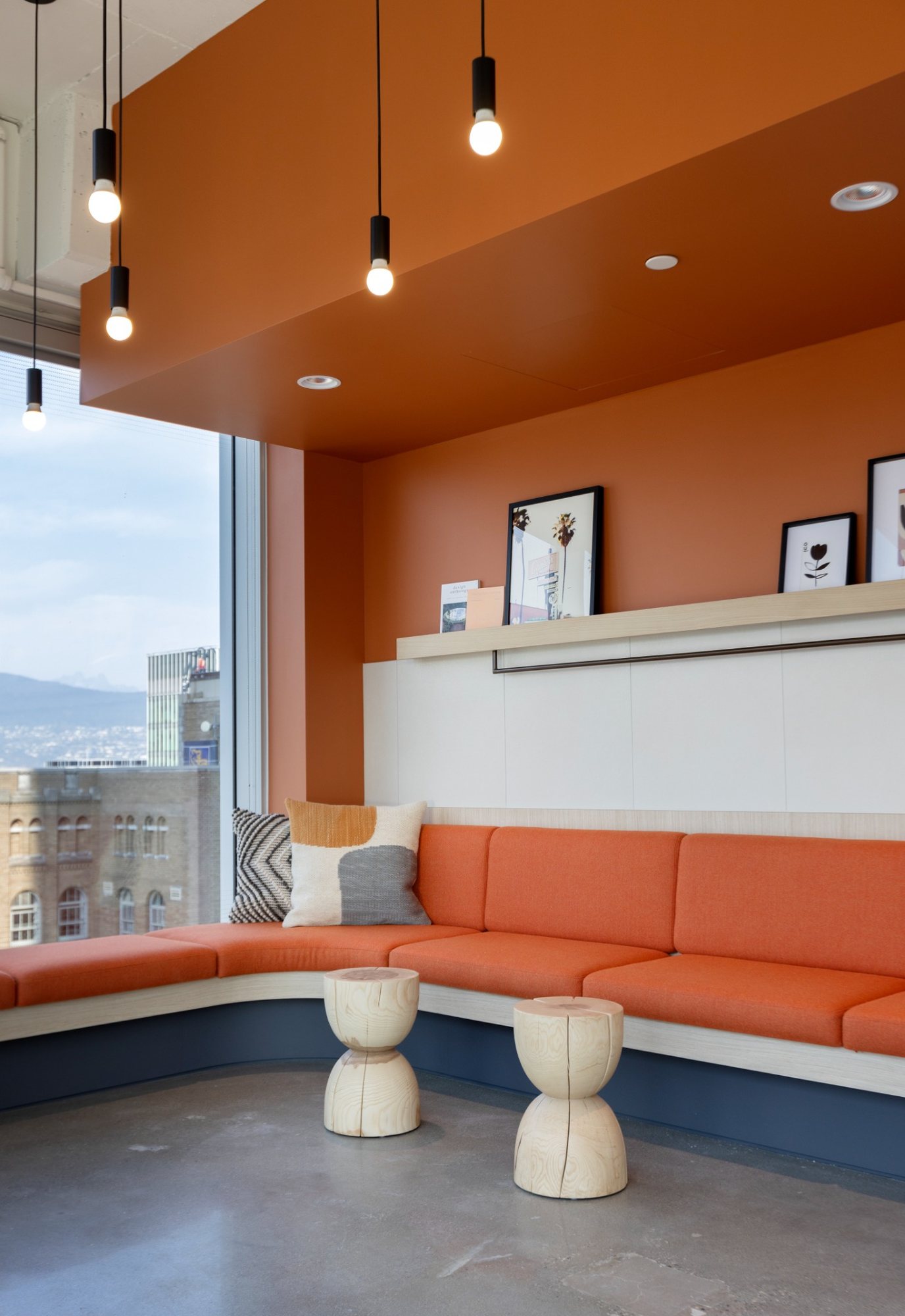 Finished commercial lounge with orange seating and pendant lighting